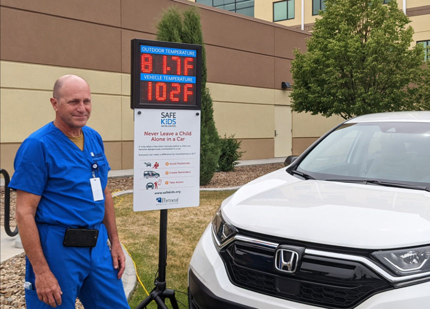 PMC Trauma Medical Director Dr. Drew McRoberts stands next to a thermometer display that shows the temperatures both inside and outside of a vehicle.